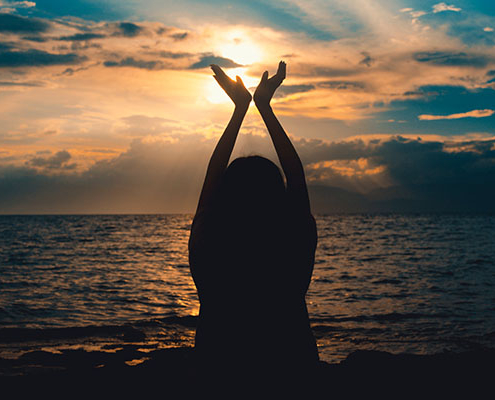 Silhouette Photo Of A Woman Holding Her Hands Up In The Air Near An Ocean